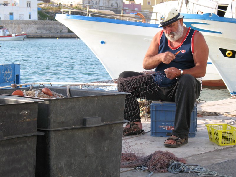 Pescatore artigianale mentre ripara le reti nel porto di Lampedusa